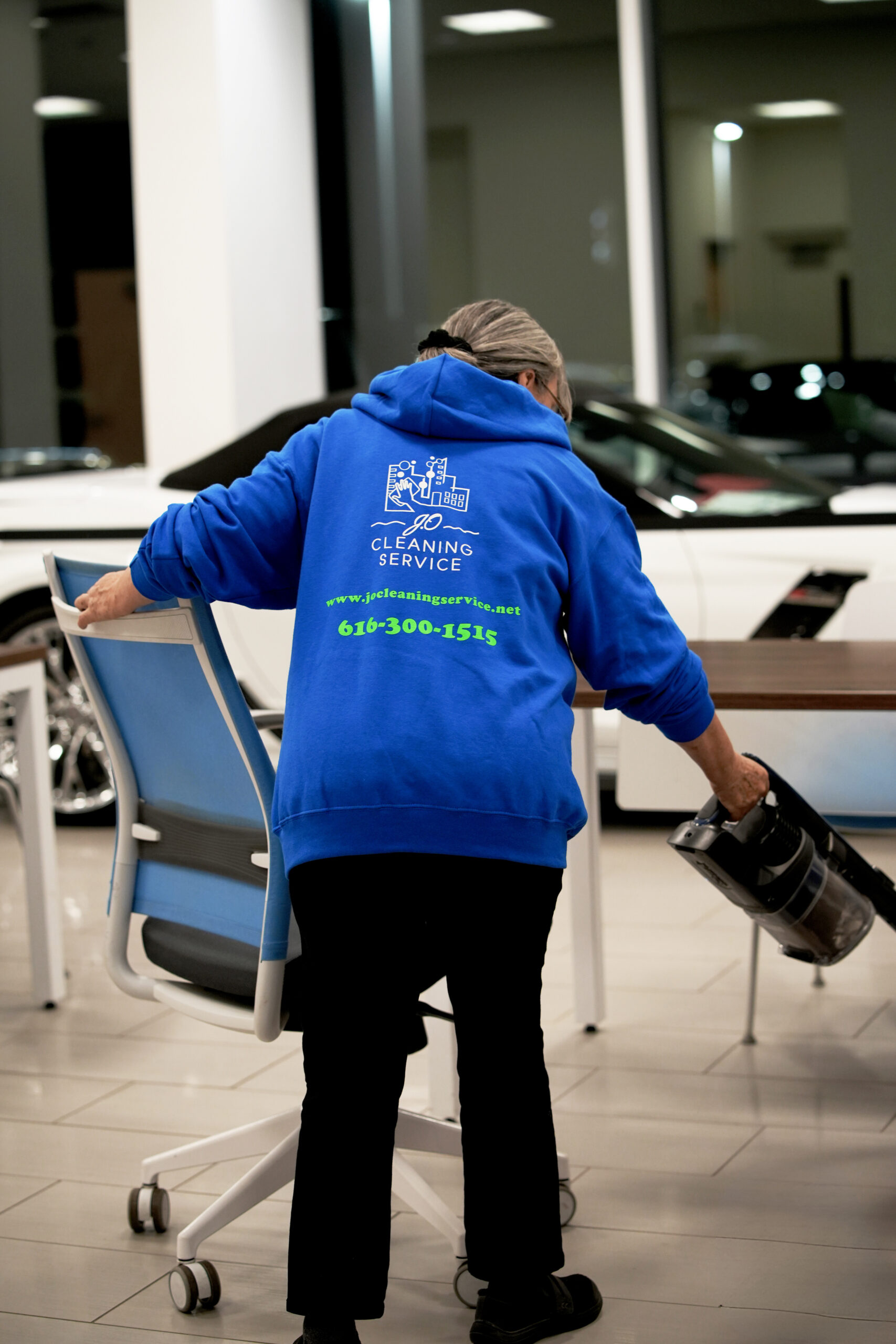 A woman in a blue shirt holding a vacuum